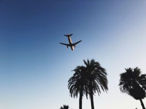 Airplane in Mid Air Above Trees during Day